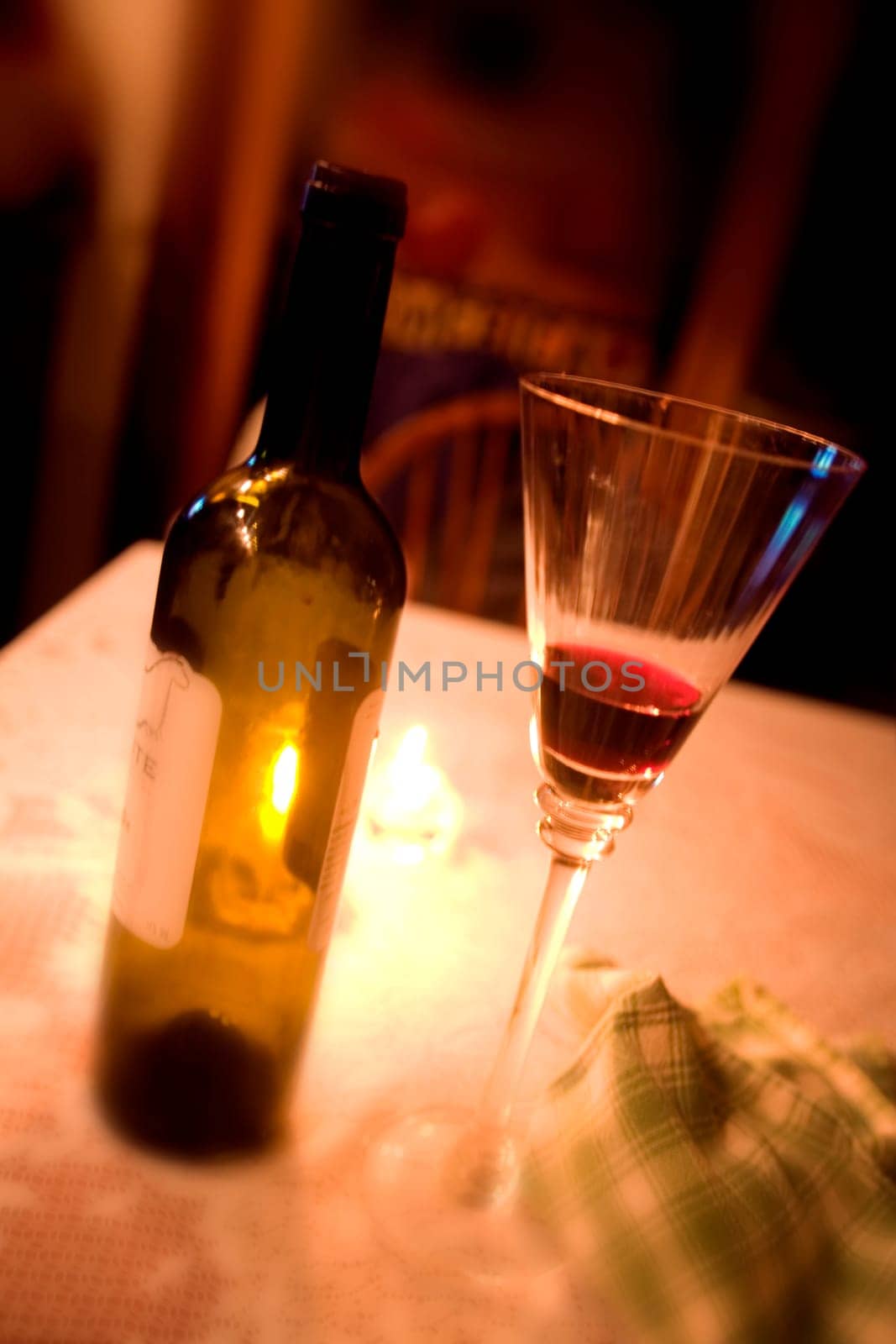 An empty wine bottle and wine glass on a table.
