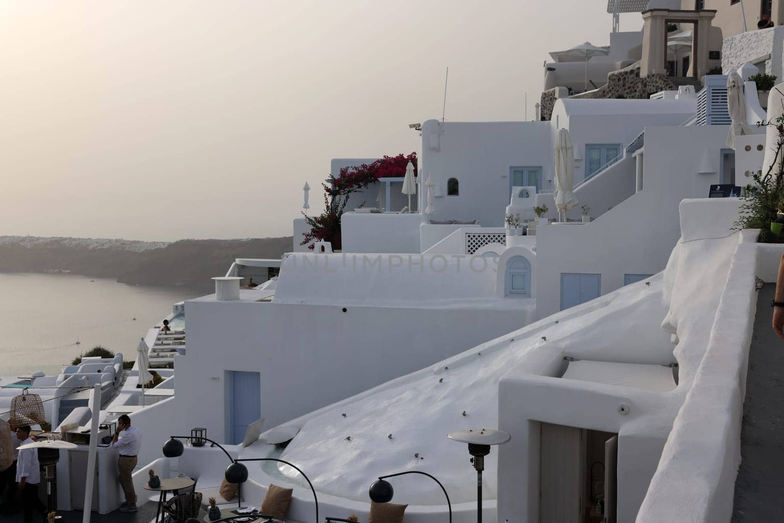 Imerovigli, Santorini, Greece - July 1, 2021: Whitewashed houses with terraces and pools and a beautiful view in Imerovigli on Santorini island, Greece