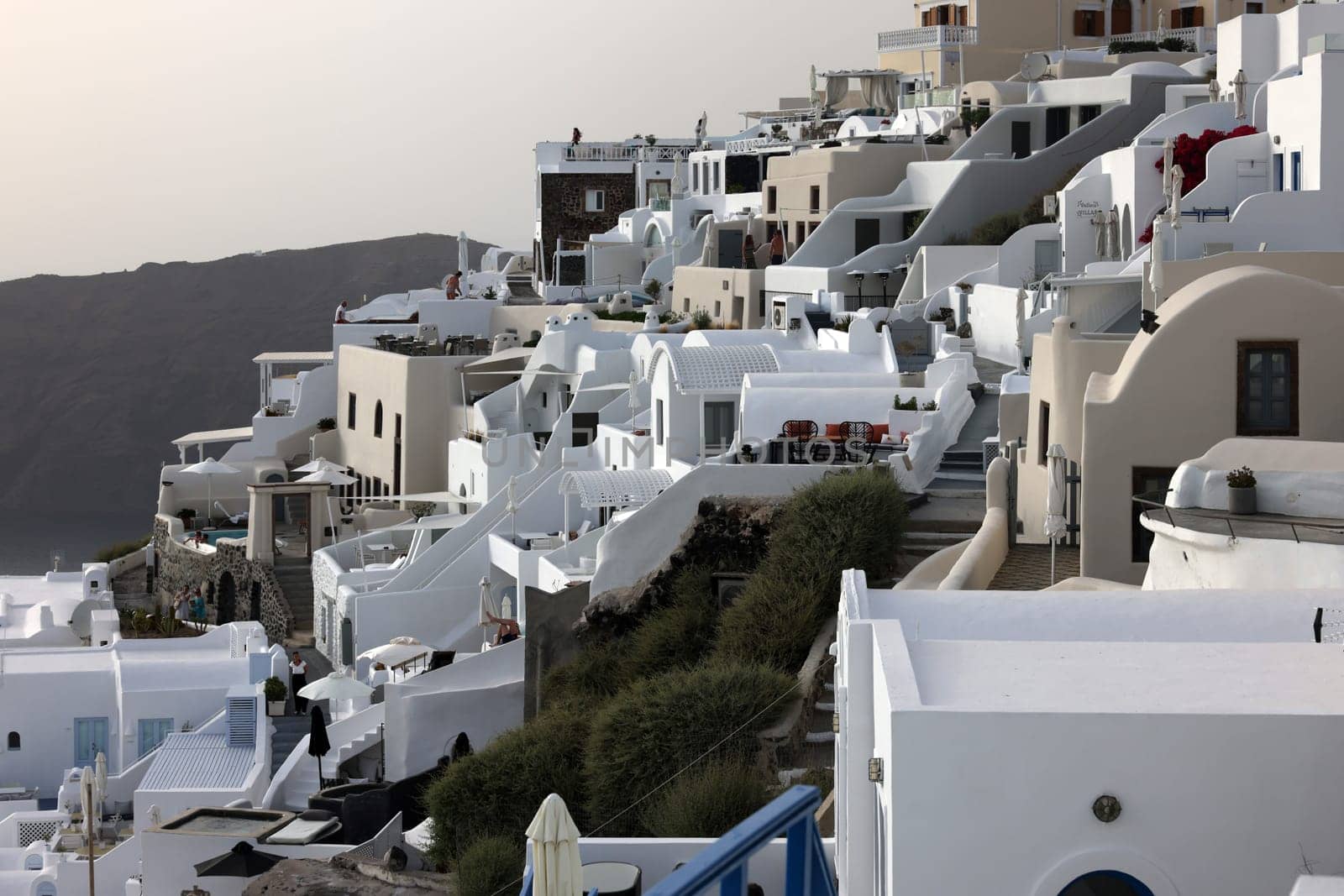 Imerovigli, Santorini, Greece - July 1, 2021: Whitewashed houses with terraces and pools and a beautiful view in Imerovigli on Santorini island, Greece