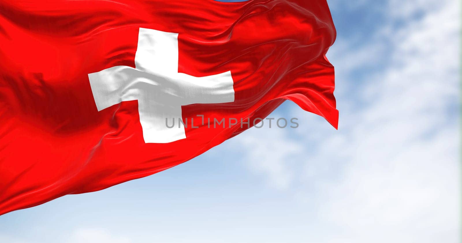 Close-up view of the swiss national flag waving in the wind. Switzerland is a landlocked country located in Europe. Fabric textured background. Selective focus