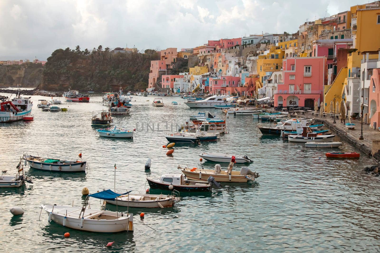 View of the Port of Corricella with lots of colorful houses on a sunny day in Procida Island, Italy.