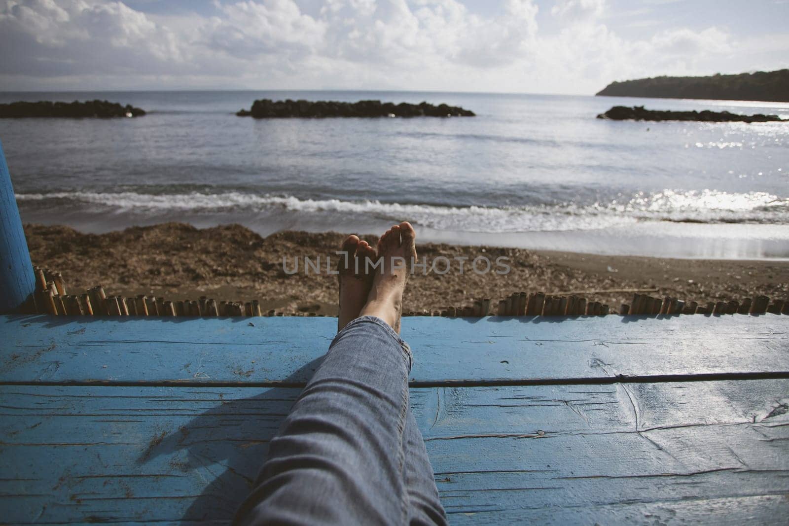 Closeup photo of women's legs on the blue wooden pier over the sea, summer vacation concept