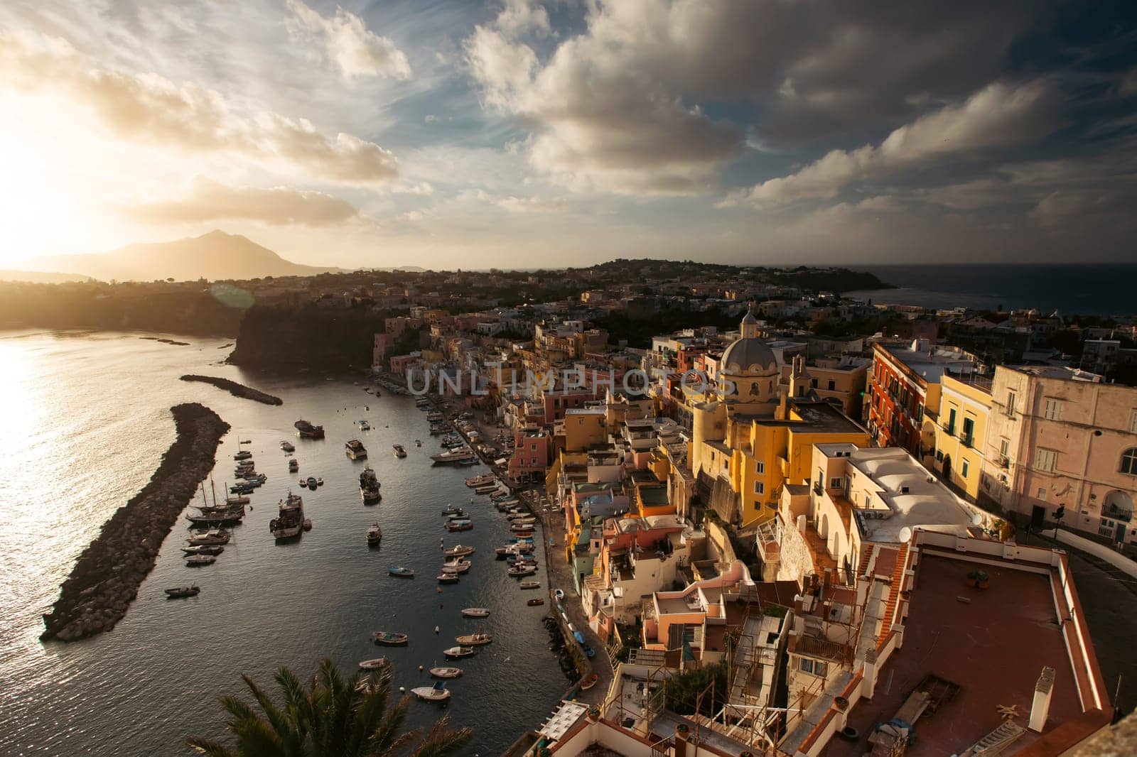 View of the Port of Corricella with lots of colorful houses in the sunset, Procida Island, Italy.