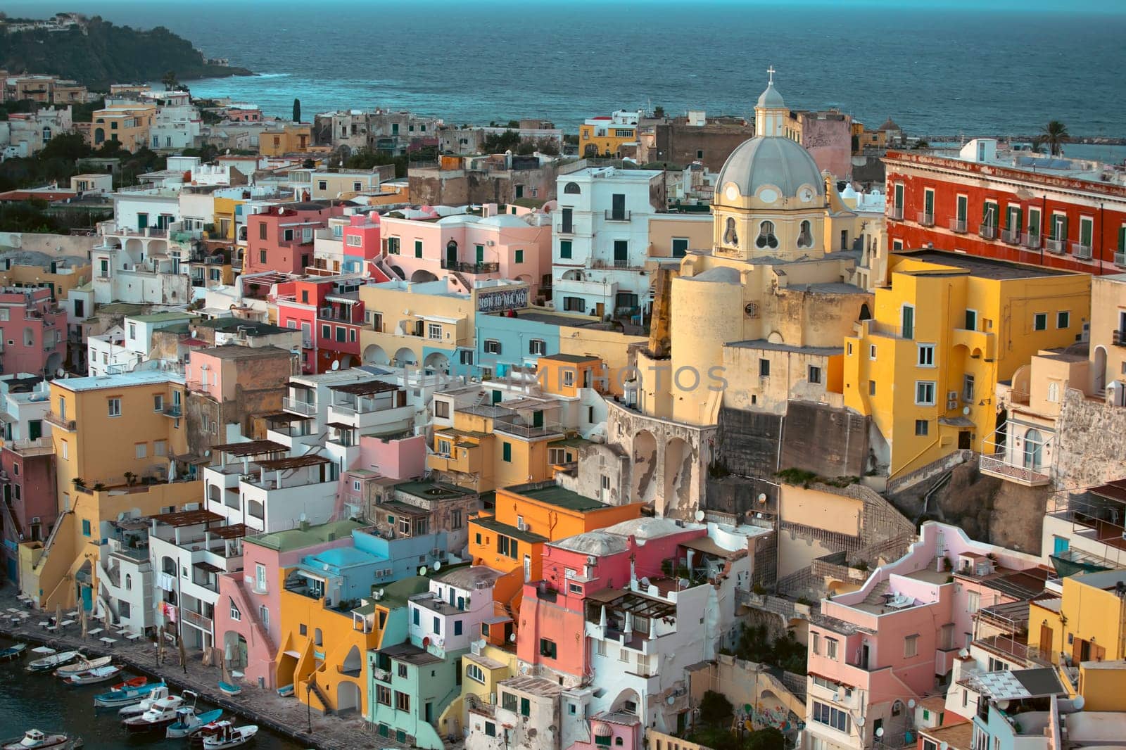 View of the Port of Corricella with lots of colorful houses in the sunset, Procida Island, Italy.