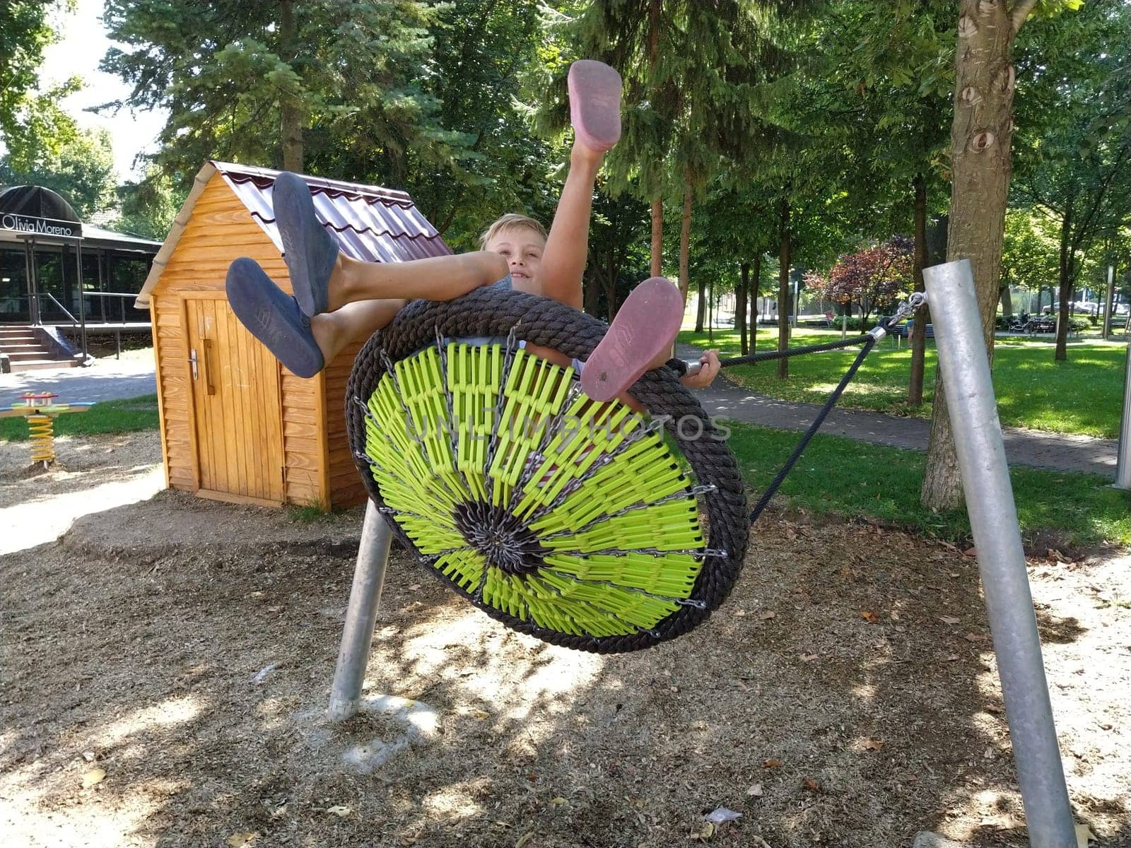 Sremska Mitrovica, Serbia, 13 September 2020. Children swing on a spider-web swing. Boy and girl, brother and sister in the summer on the playground. Swinging the swing.