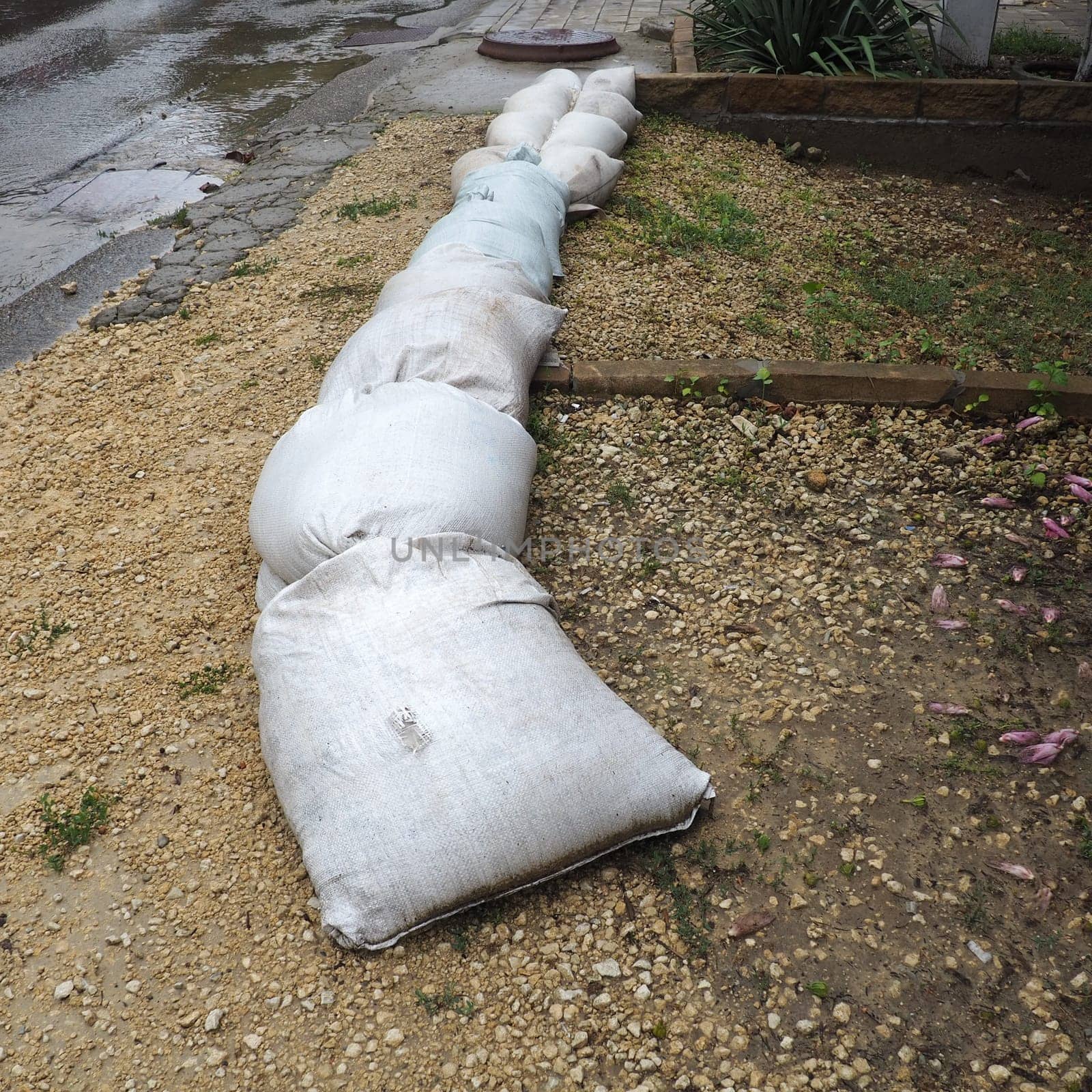 Sandbags are placed on the ground next to the road to prevent flooding and overflow. Home protection from bad weather, cyclone and hurricanes. Insurance case. Anapa, Krasnodar, Russia, August 2021.