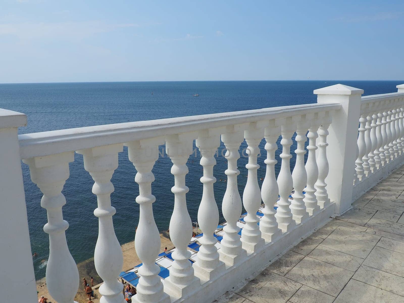 Anapa, Russia 23 August 2021. Balustrade overlooking the sea, sky and horizon, a fence consisting of a row of curly posts of balusters connected by a horizontal beam. Railing from curly white posts