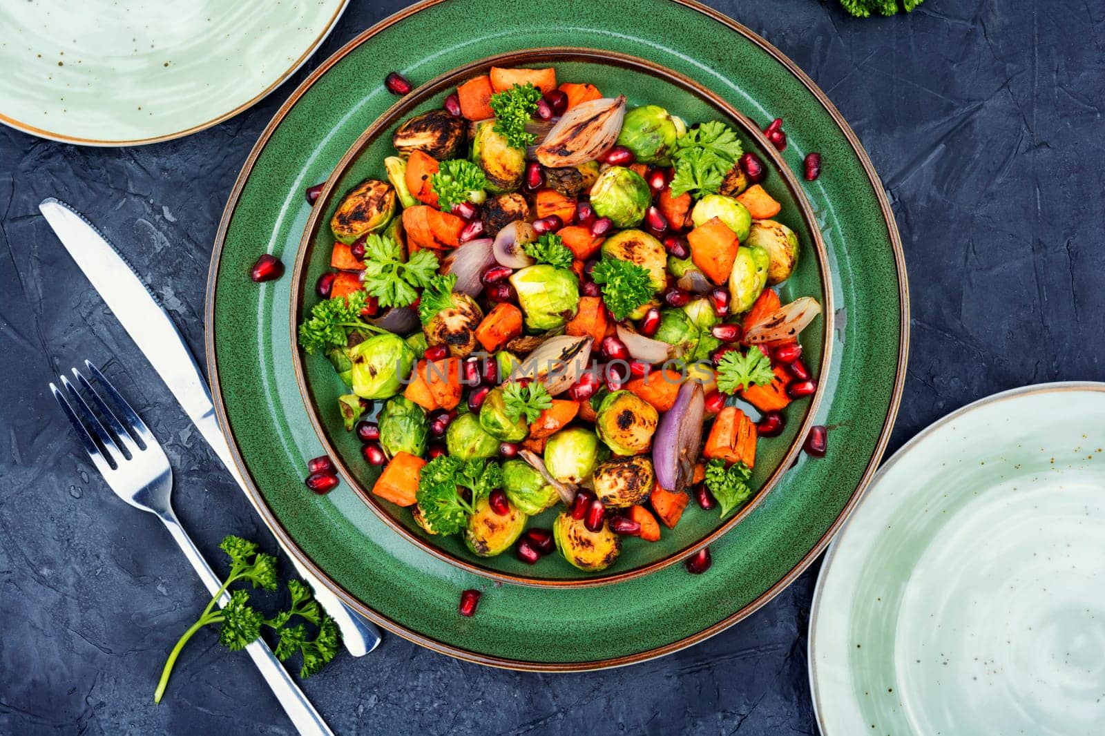 Salad with grilled brussels sprouts, roasted carrots, garnished with herbs and pomegranate seeds. Top view