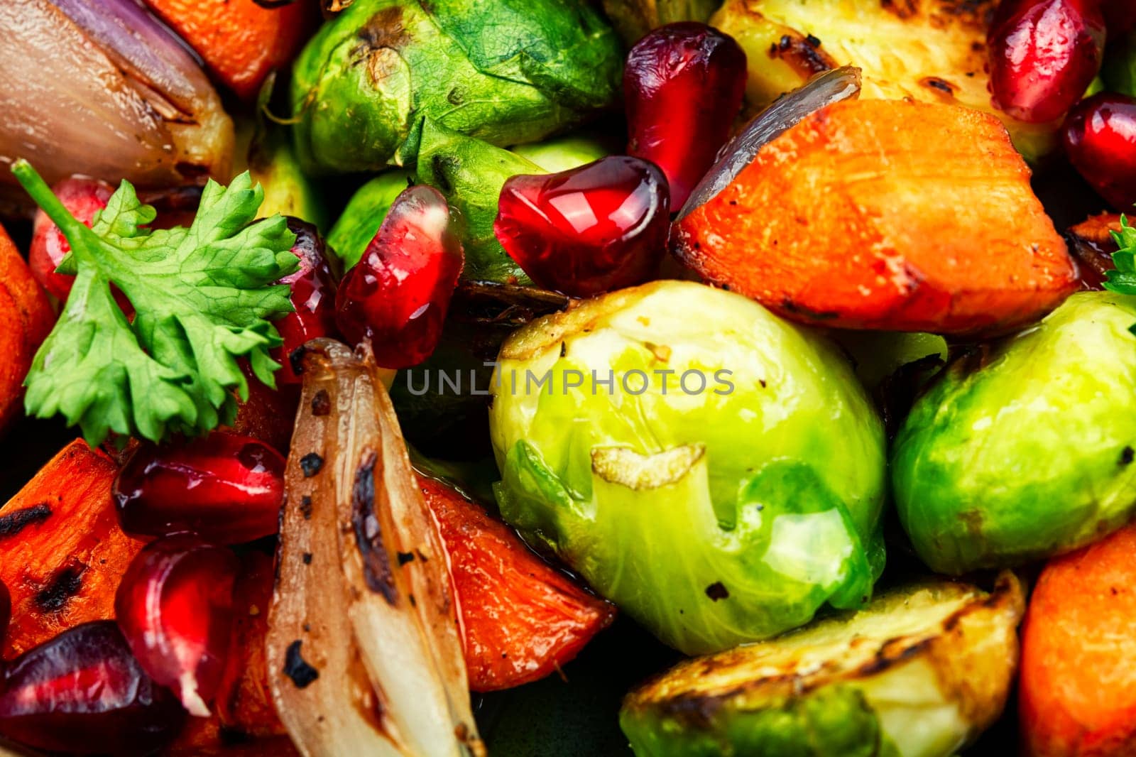 Salad with grilled brussels sprouts, roasted carrots, garnished with herbs and pomegranate seeds. Top view