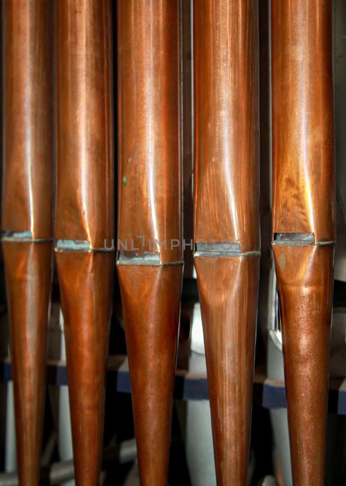 Many organ pipes stand side by side in an organ over a bellows.