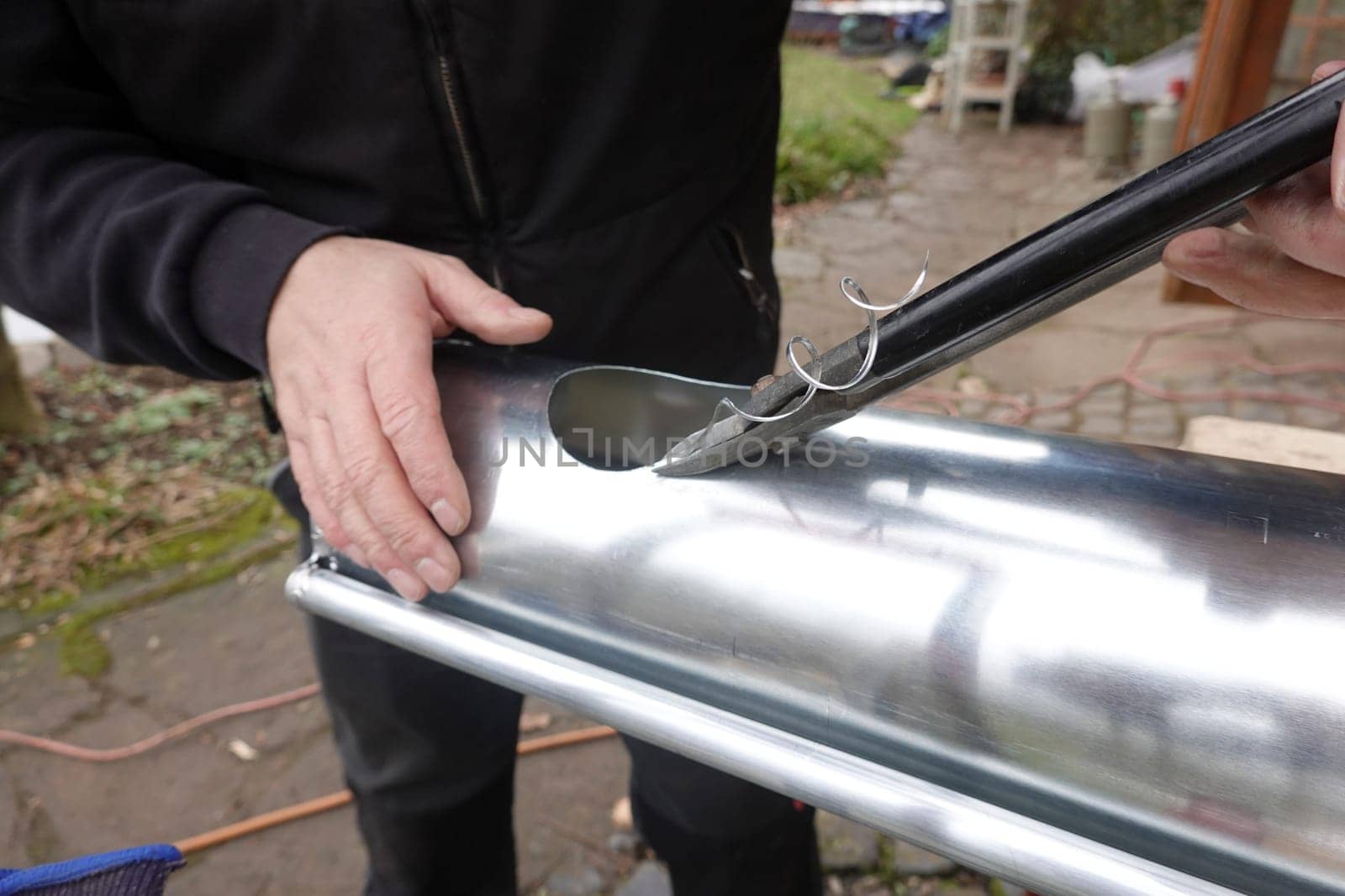 Dachdecker schneidet ein Loch für Ablaufstutzen in Dachrinne