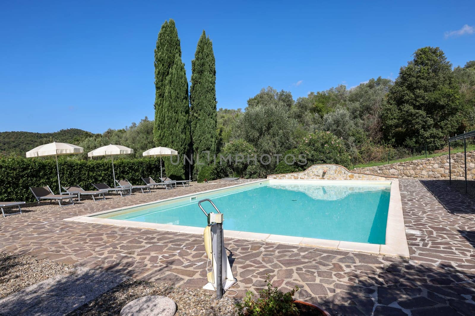 A swimming pool on the Montemassi hillside surrounded by cypresses and oleanders n the province of Grosseto. Italy