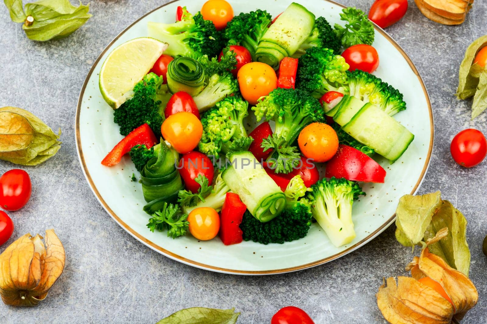 Fresh salad with broccoli, tomato, cucumber and physaliswinter cherry . Food background