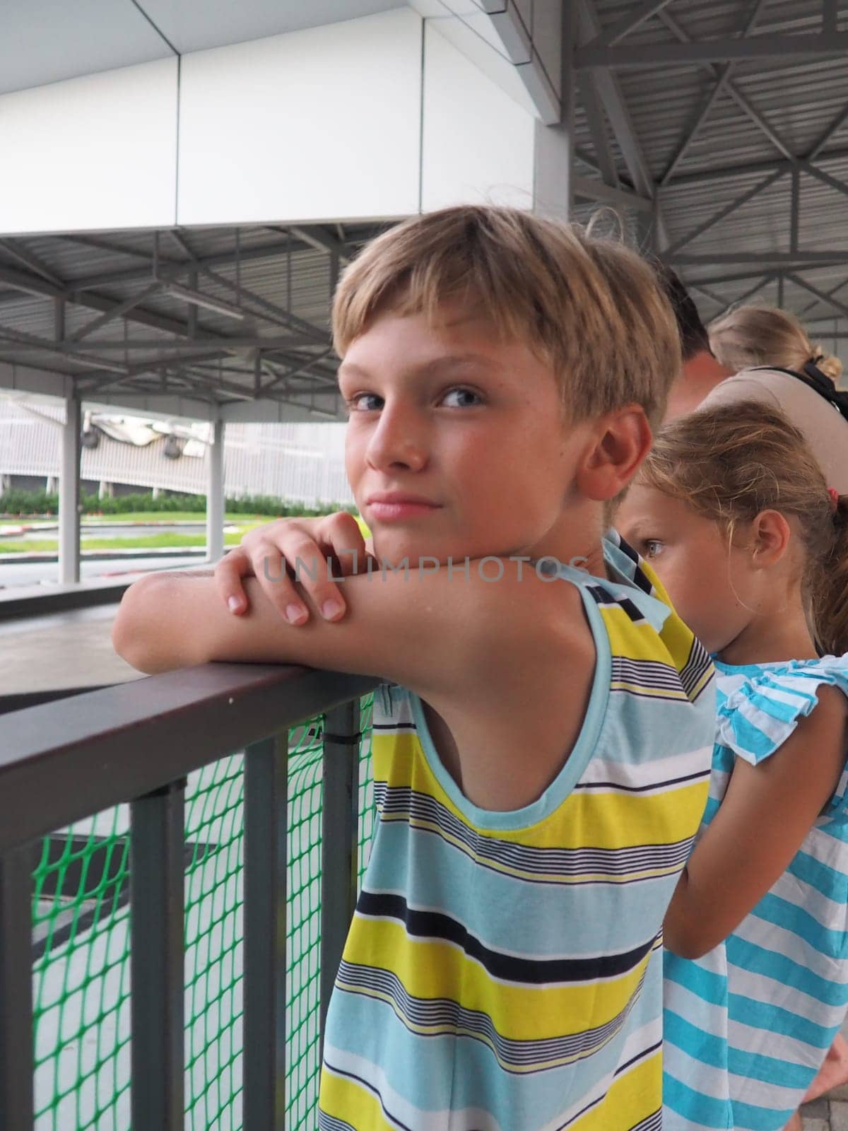 Anapa, Russia, 08.17.2021, boy and girl at the karting stadium. Karting is a sport and entertainment, racing on karts - racing cars without a body. Children stand at the fence. Sports gambling event