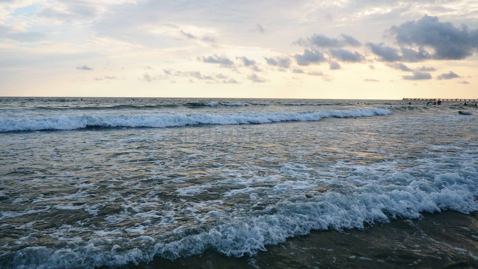 Sunset over the sea. Beautiful waves at sunset. Tourist mecca, resort. Evening sky. The rays are reflected from the water