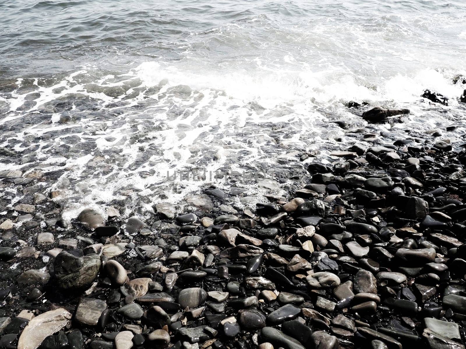 Sea rocky beach with waves Sukko, Anapa, Krasnodar Territory, Russia. Sea foam on a pebble beach view from above. Large rounded pebbles and boulders in the water. Horizontal photo Black Sea, Caucasus