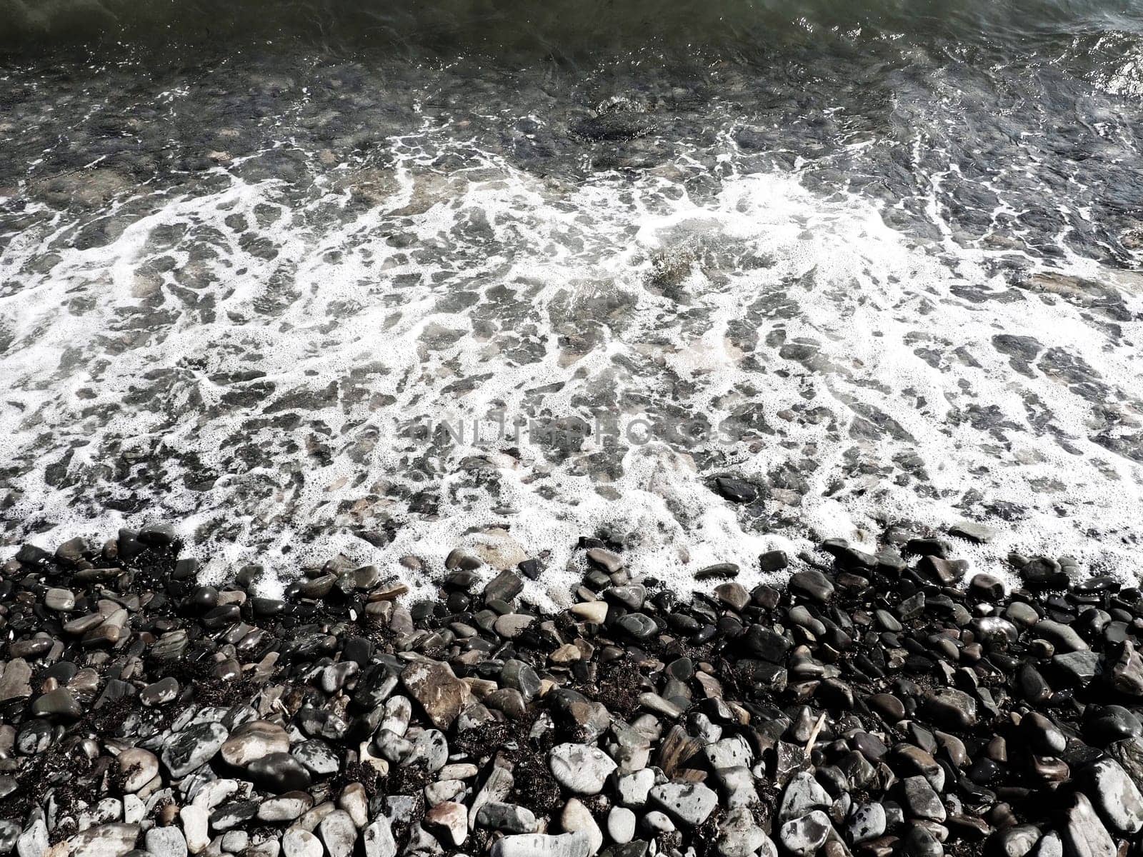 Sea rocky beach with waves Sukko, Anapa, Krasnodar Territory, Russia. Sea foam on a pebble beach view from above. Large rounded pebbles and boulders in the water. Horizontal photo Black Sea, Caucasus