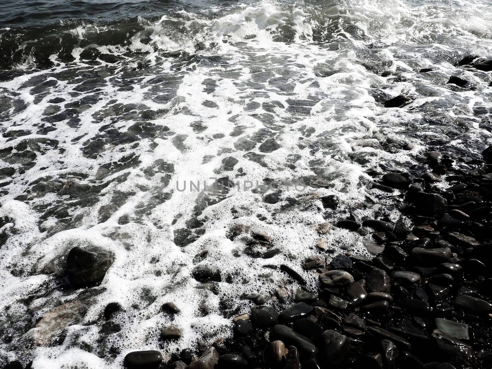 Sea rocky beach with waves Sukko, Anapa, Krasnodar Territory, Russia. Sea foam on a pebble beach view from above. Large rounded pebbles and boulders in the water. Horizontal photo Black Sea, Caucasus
