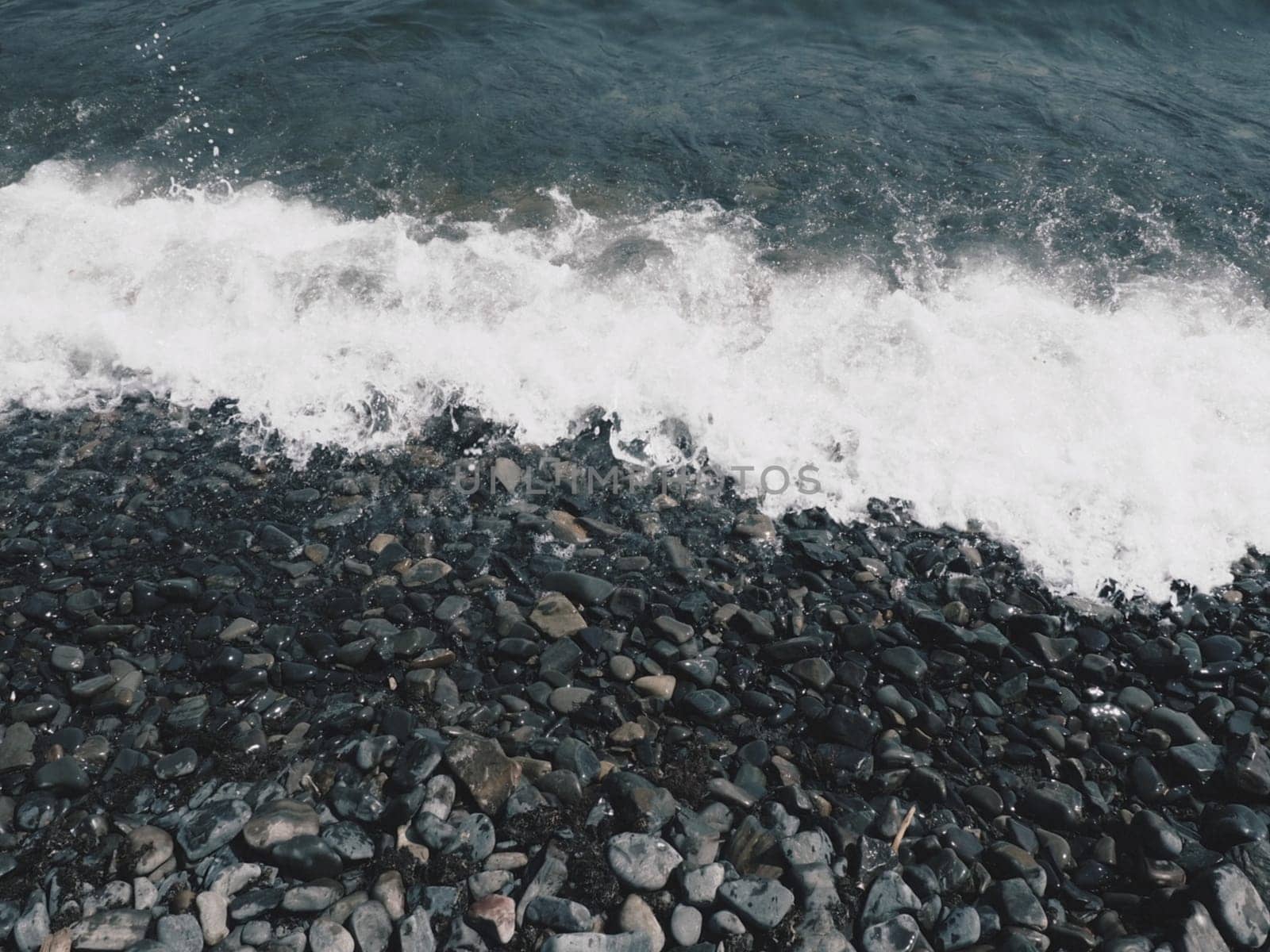 Sea rocky beach with waves Sukko, Anapa, Krasnodar Territory, Russia. Sea foam on a pebble beach view from above. Large rounded pebbles and boulders in the water. Horizontal photo Black Sea, Caucasus