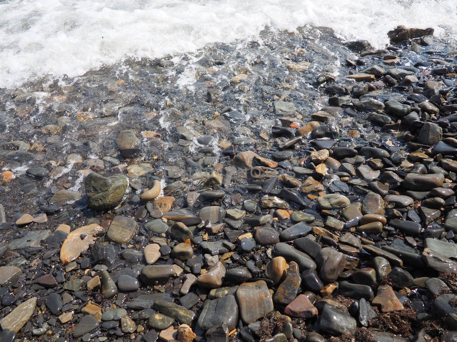 Sea rocky beach with waves Sukko, Anapa, Krasnodar Territory, Russia. Sea foam on a pebble beach view from above. Large rounded pebbles and boulders in the water. Horizontal photo Black Sea, Caucasus