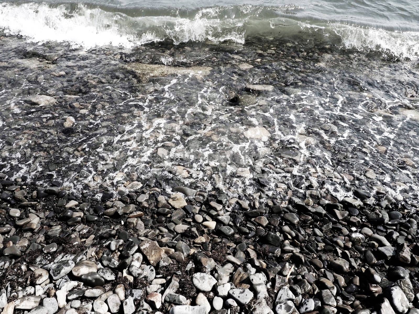 Sea rocky beach with waves Sukko, Anapa, Krasnodar Territory, Russia. Sea foam on a pebble beach view from above. Large rounded pebbles and boulders in the water. Horizontal photo Black Sea, Caucasus