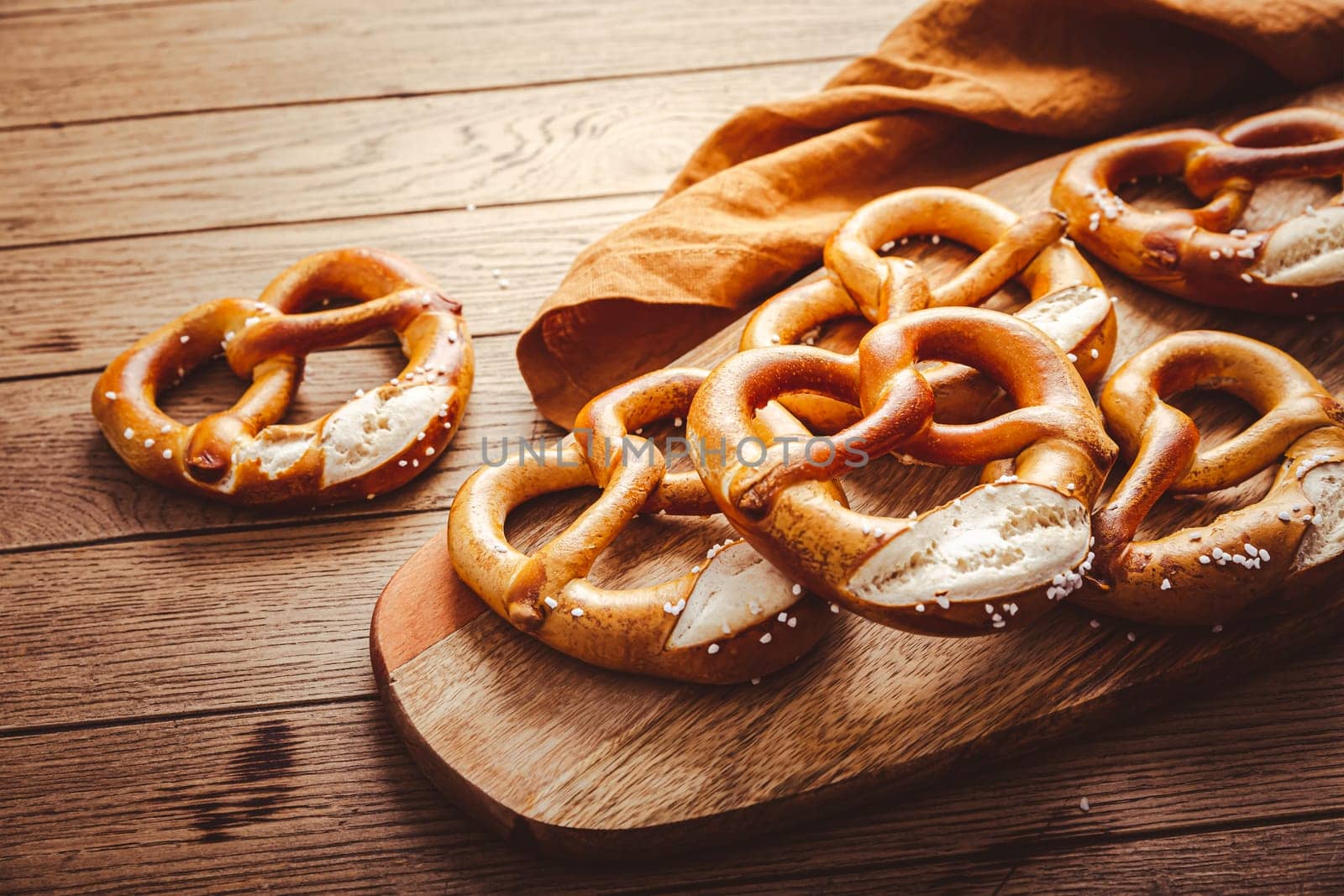 Fresh baked homemade German pretzel with sea salt on wooden table. Classic beer snack, baked pastry.