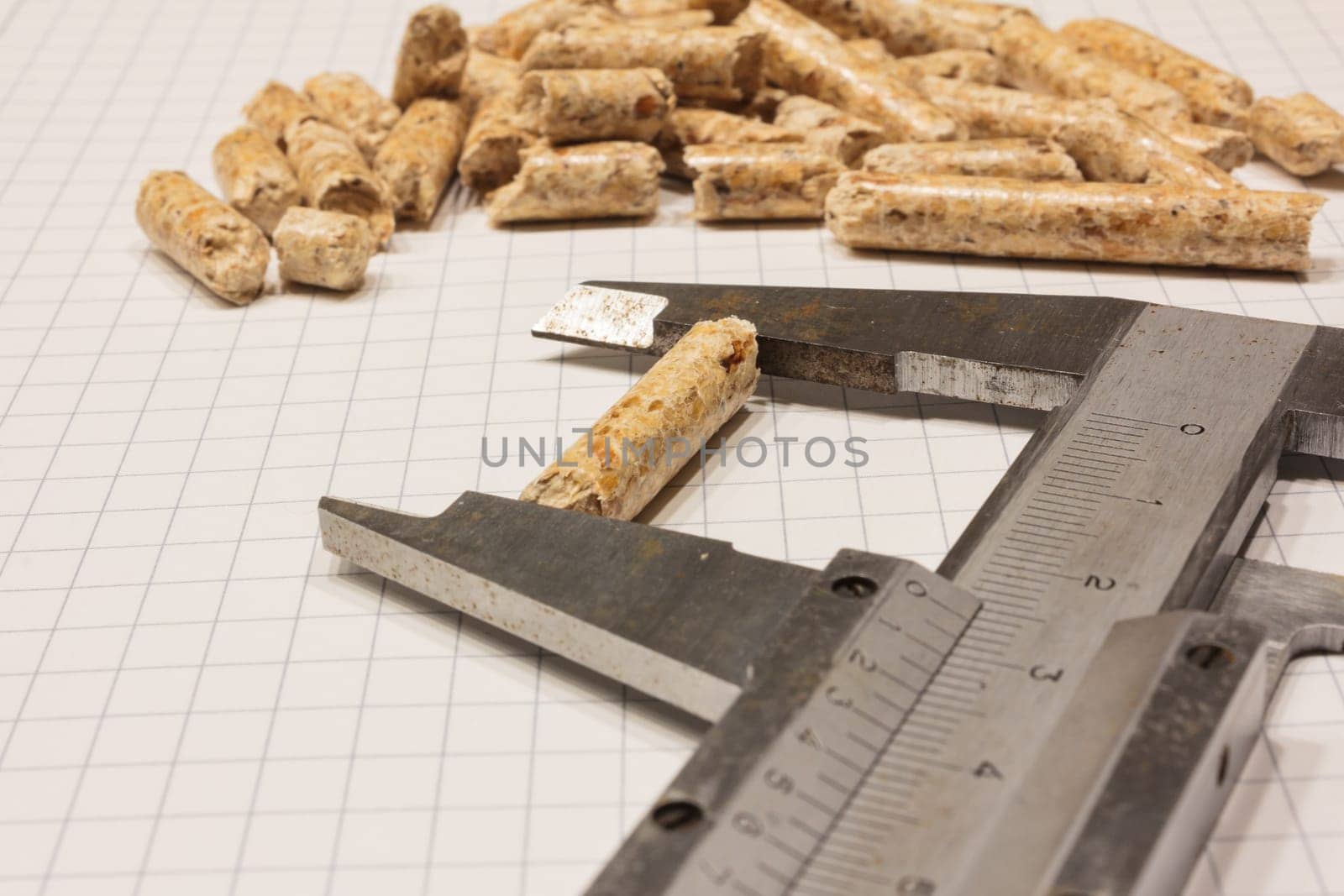 Quality control of certified wood pellets with caliper and sieve on chequered paper