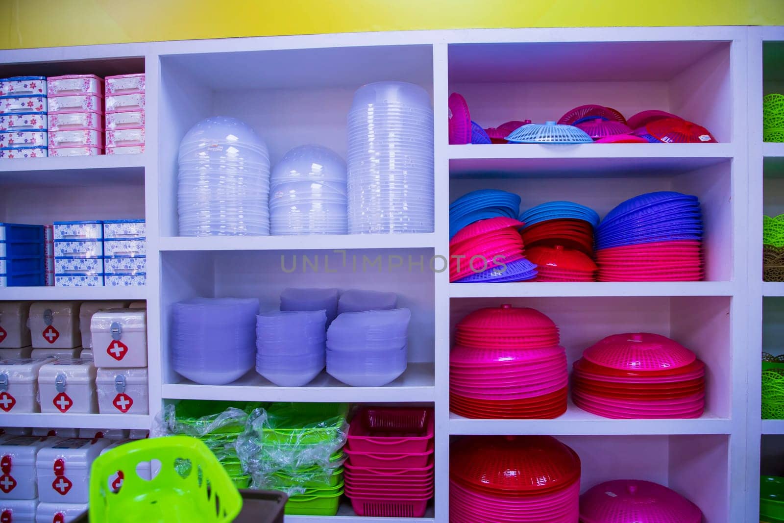 Colorful plastic tableware on shelves in the super shop. Close-up.