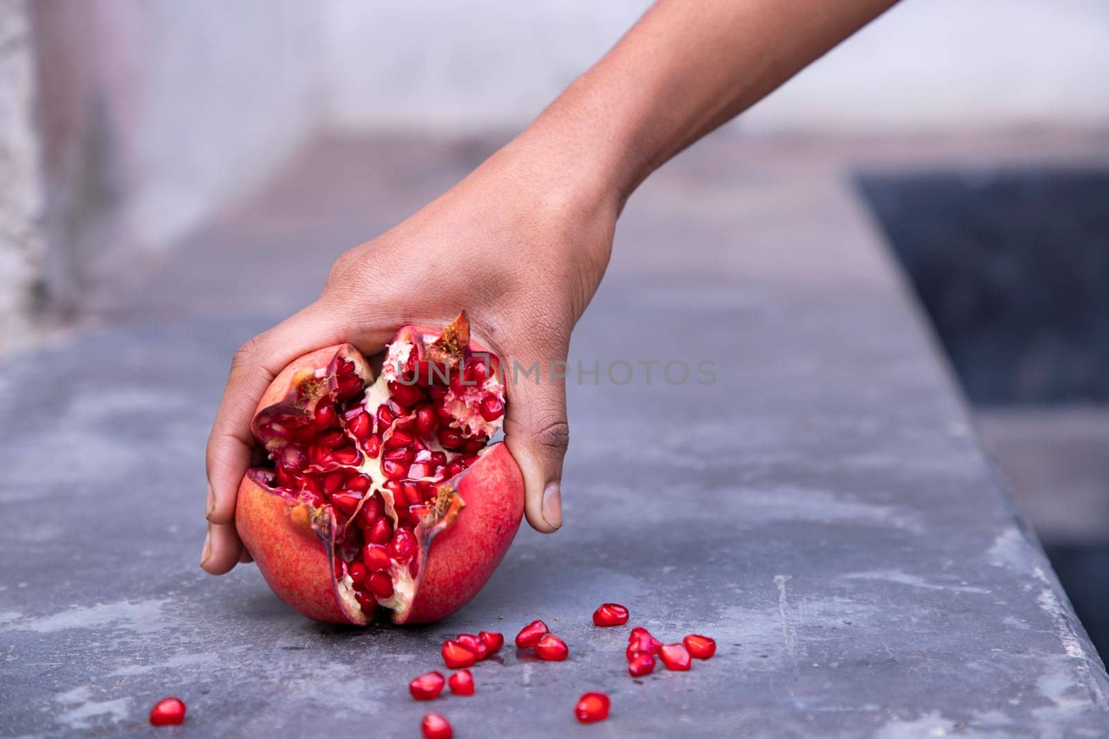Pomegranate fruit in hand on stone background, close up