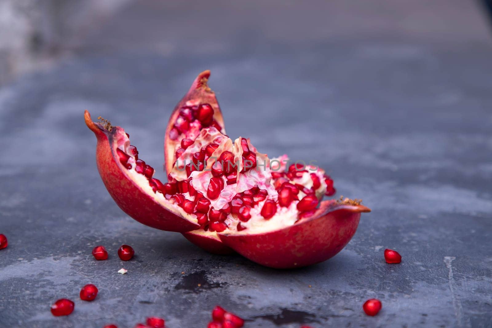 Ripe pomegranate fruit on a dark stone background.
