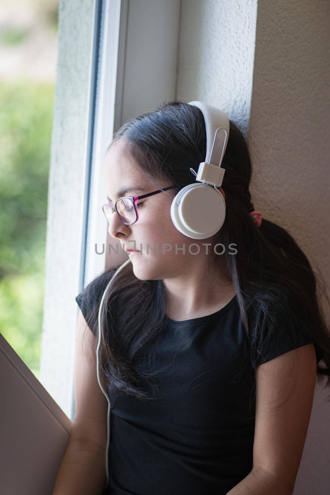Cute happy girl with glasses listening to music on headphones