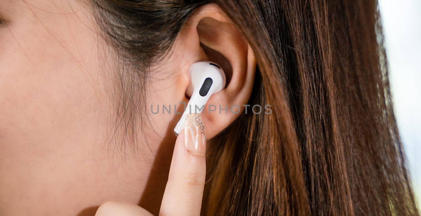 Close up of Happy female touching earbuds to control next listen song on mobile phone in living room at home, Lifestyle woman wearing wireless earphones listening to favorite song on her smartphone