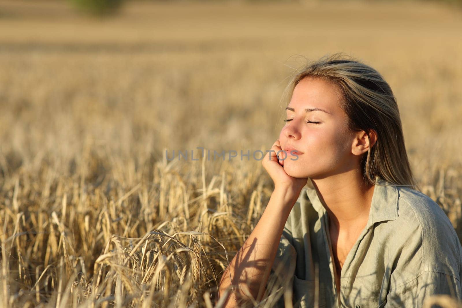 Relaxed woman in a field at sunset resting
