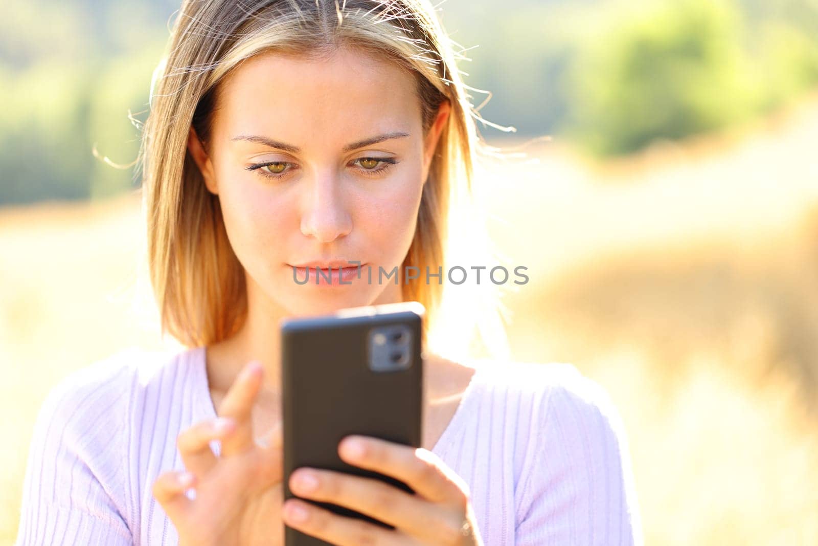 Front view portrait of a teen using cell phone in nature