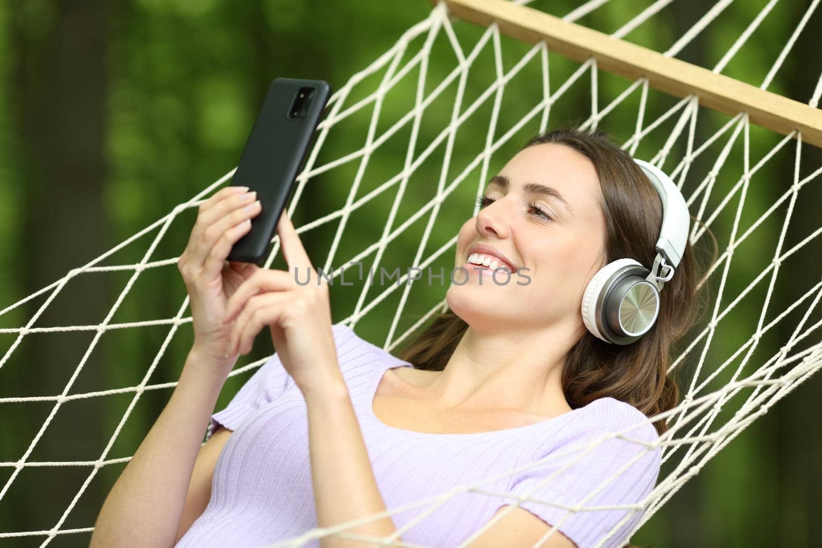 Happy woman on hammock listening music in a green forest