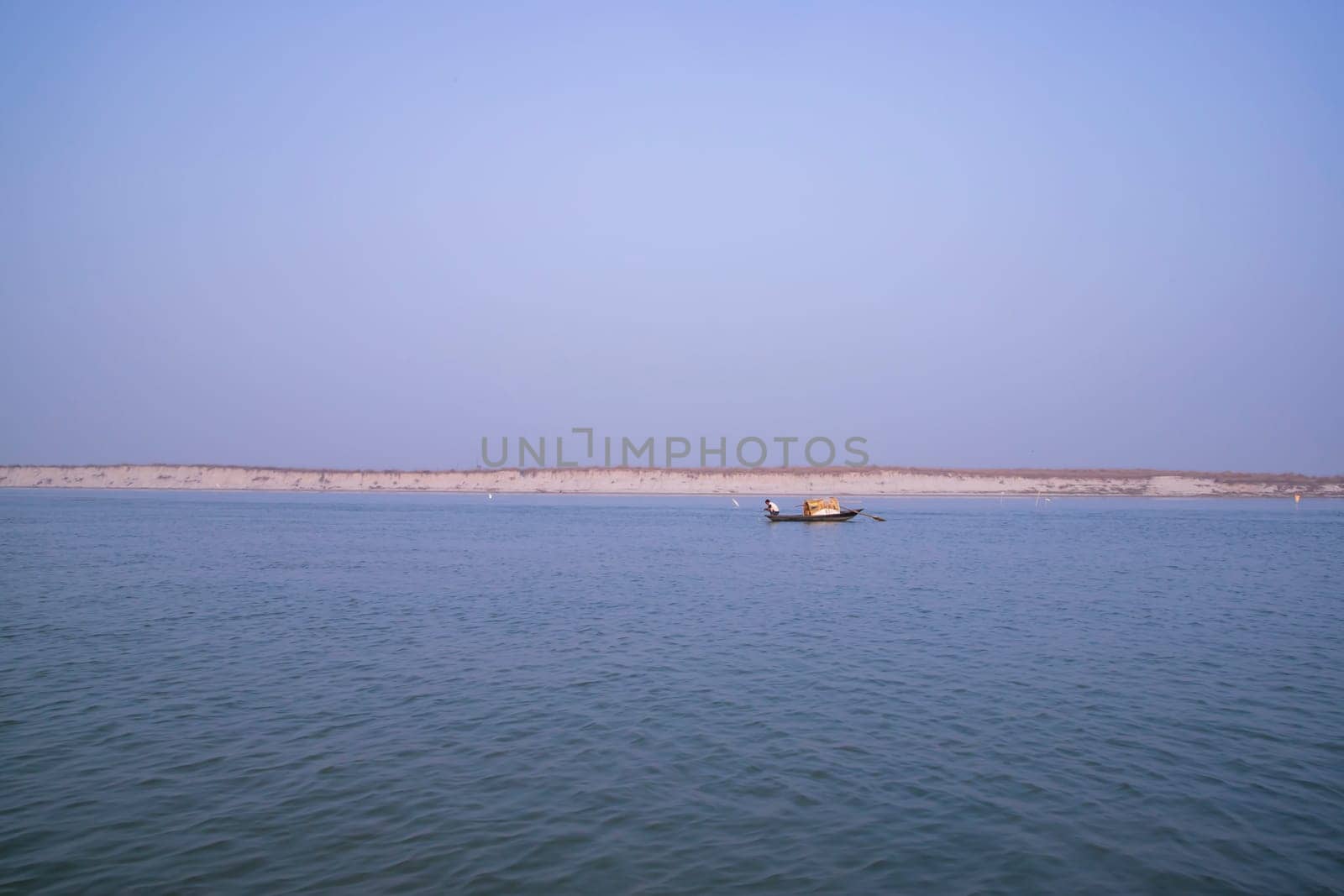 landscape view of Padma river on a fishing boat with a sand island under the blue sky