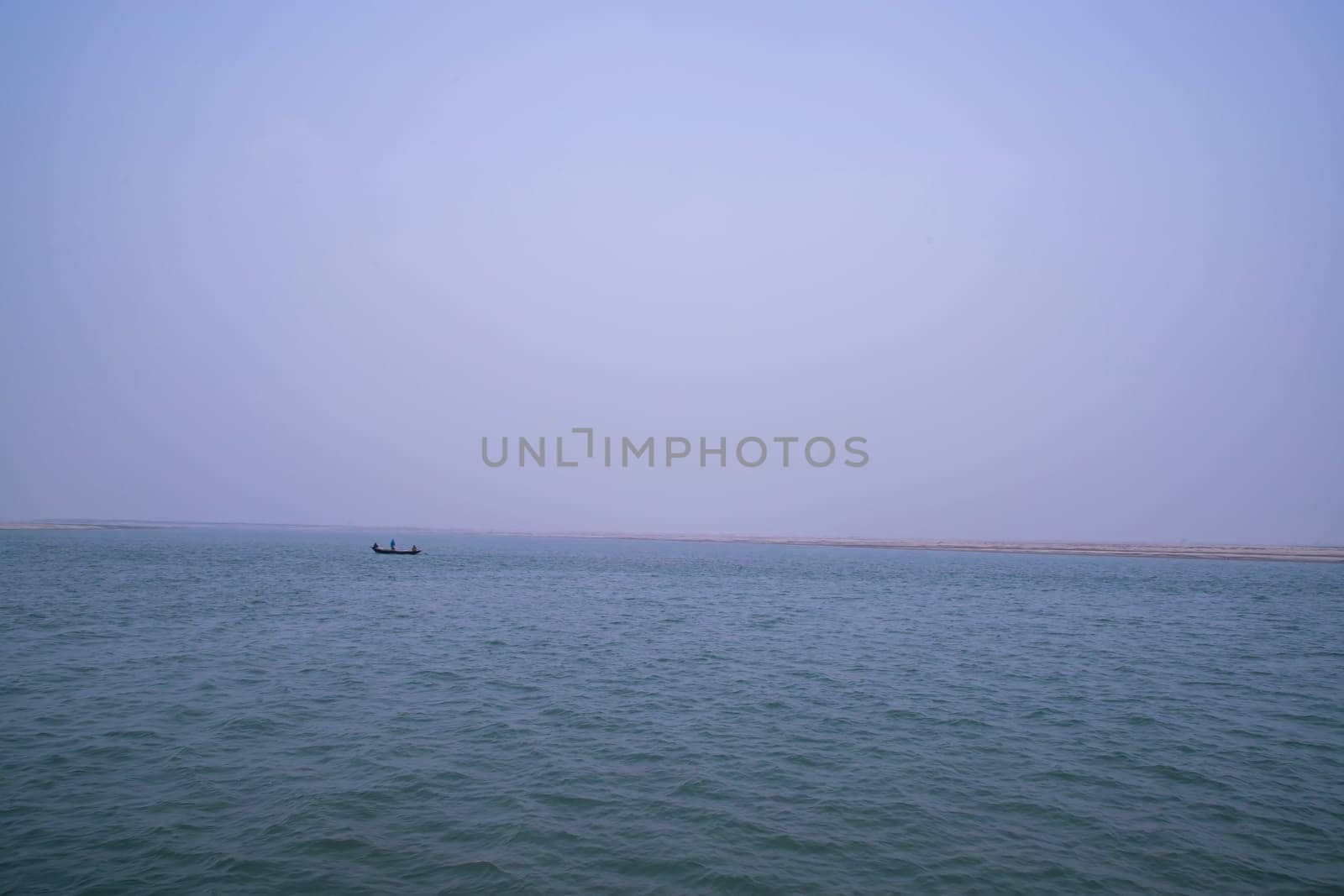 landscape view of Padma river on a fishing boat with a sand island under the blue sky