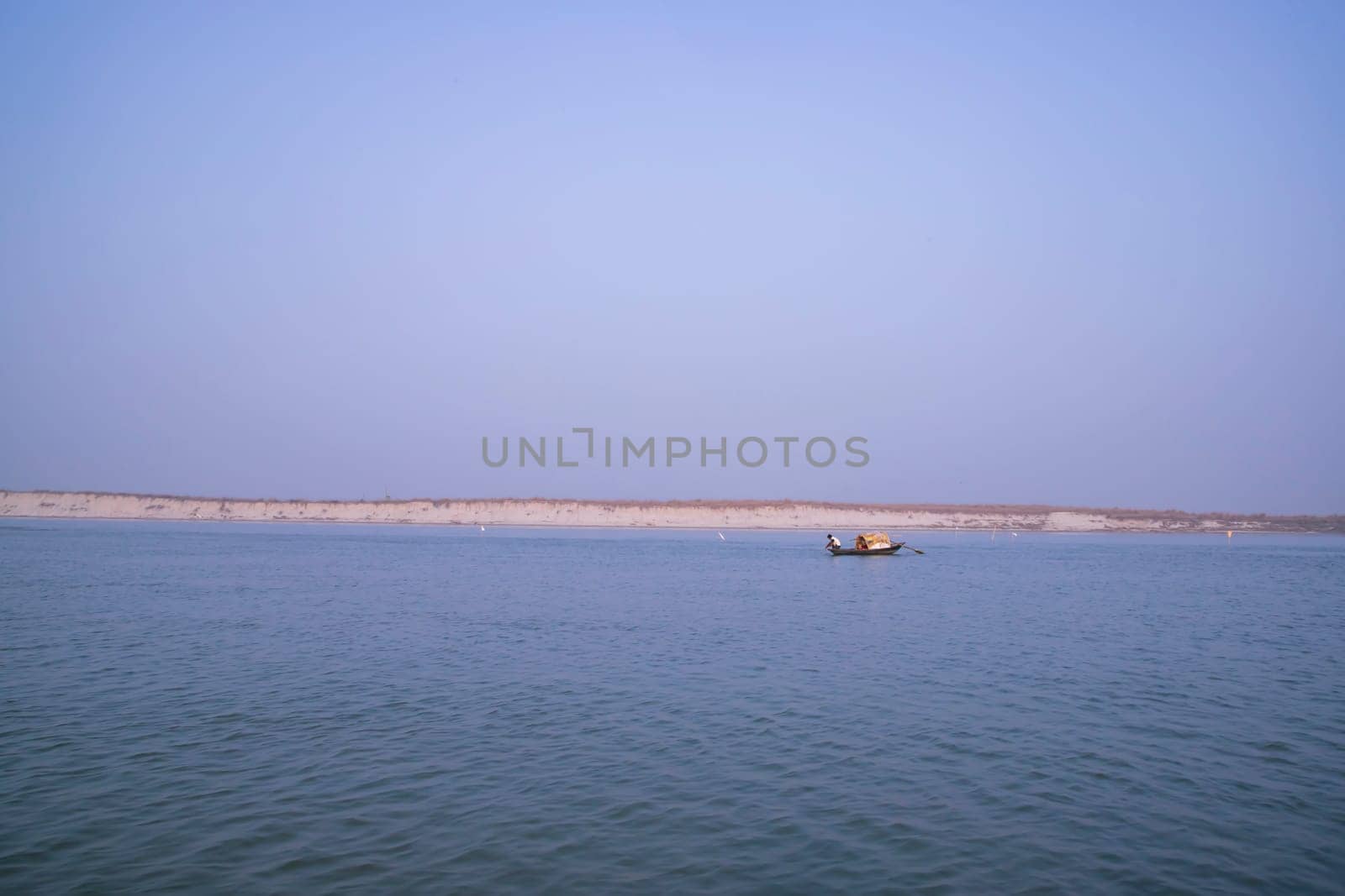 landscape view of Padma river on a fishing boat with a sand island under the blue sky