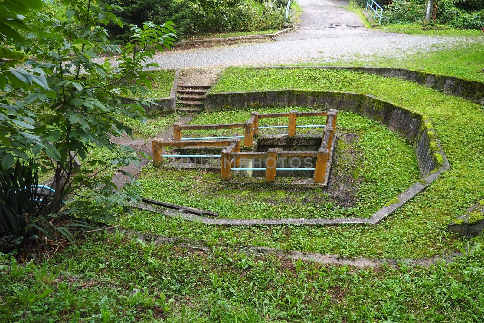 Banja Koviljaca, Loznica, Serbia. Mount Guchevo, park and forest. Source of mineral sulfuric and ferruginous water Rakina Chesma Cesma. A spring near the road to Guchevo. Concrete fence and stairs