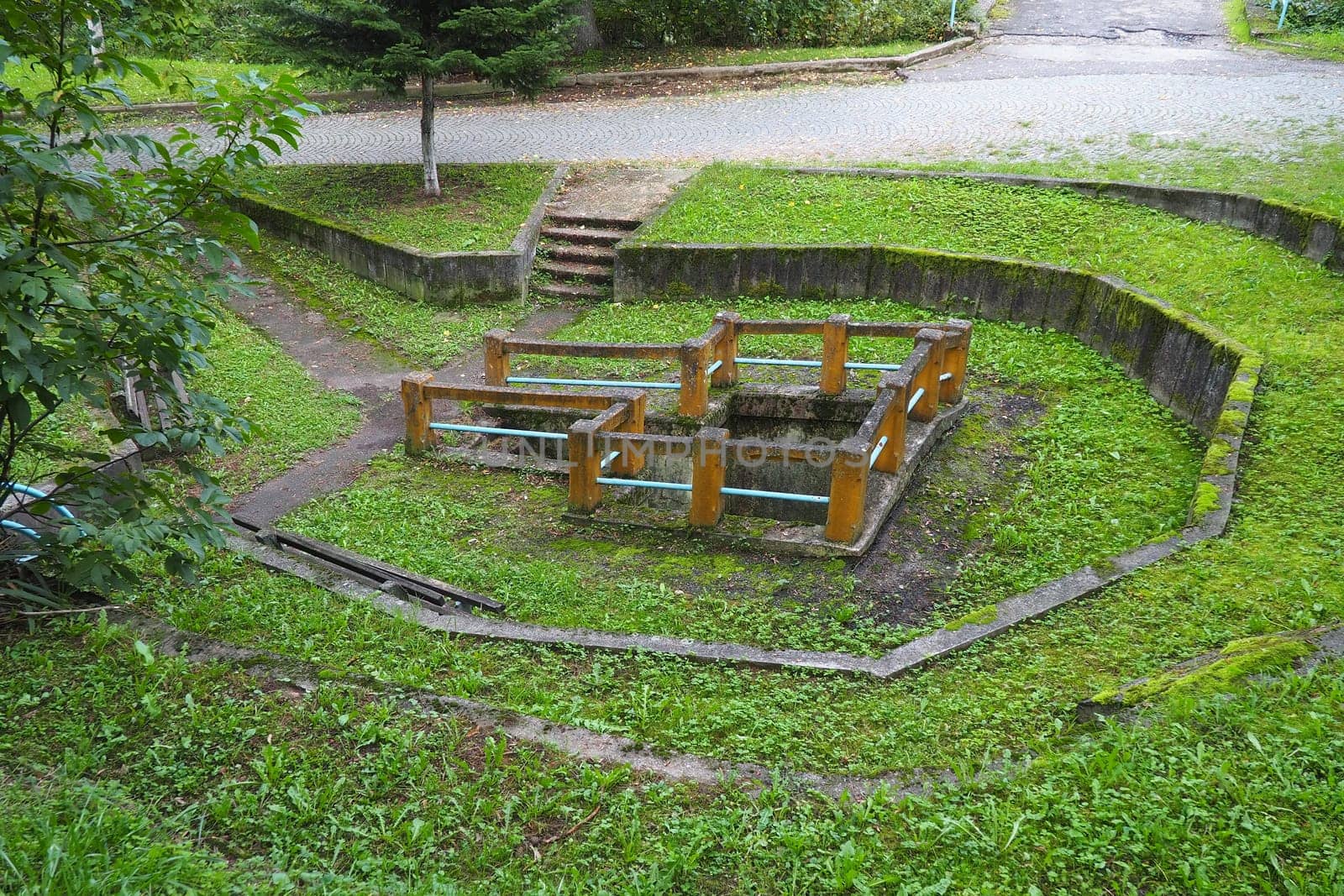 Banja Koviljaca, Loznica, Serbia. Mount Guchevo, park and forest. Source of mineral sulfuric and ferruginous water Rakina Chesma Cesma. A spring near the road to Guchevo. Concrete fence and stairs