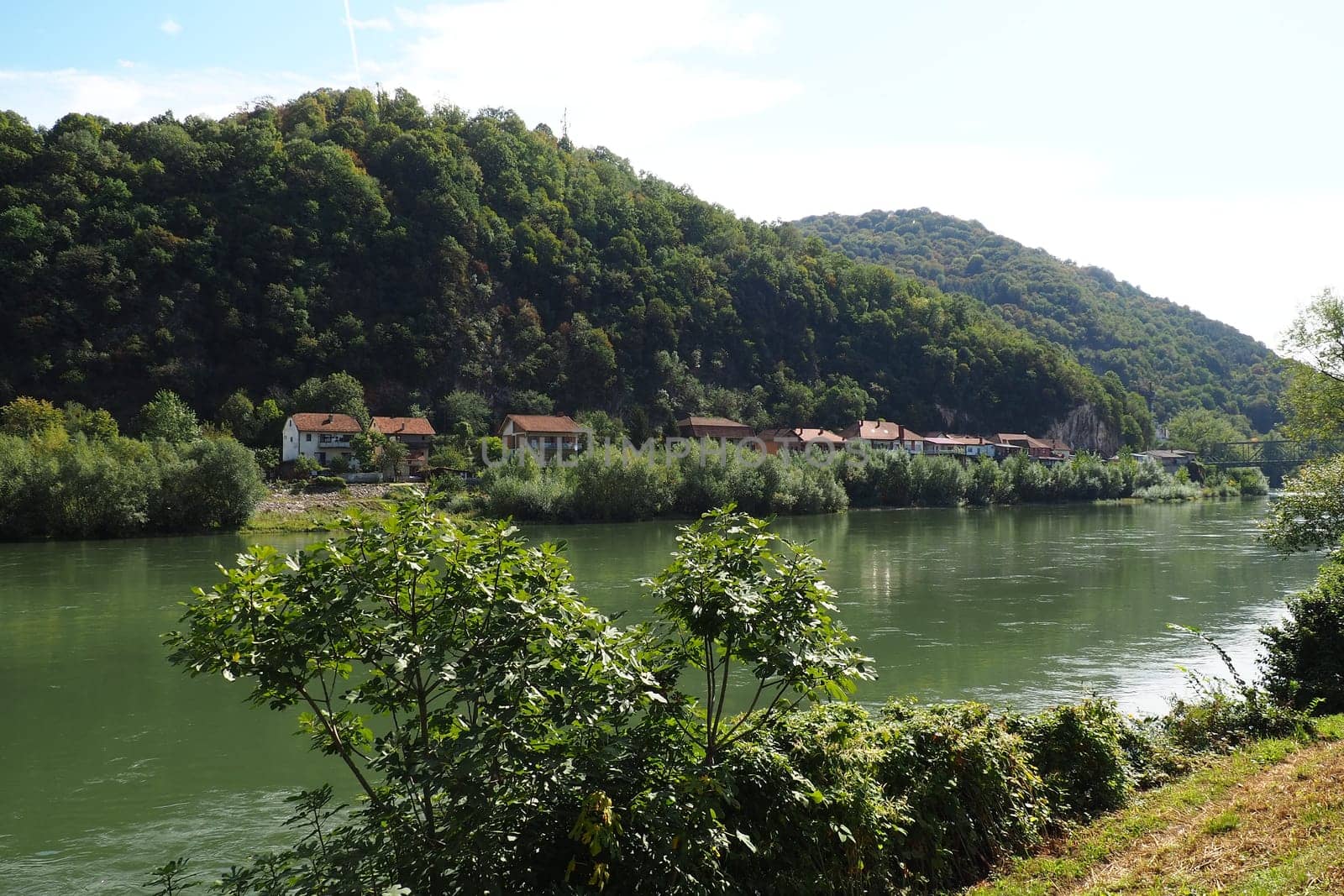 Mali Zvornik, Serbia, September 29, 2022. Drina river near Banja Koviljaca, view of the coast of Serbia from BiH. The flow of water, greenery on the opposite bank of the river. Residential houses