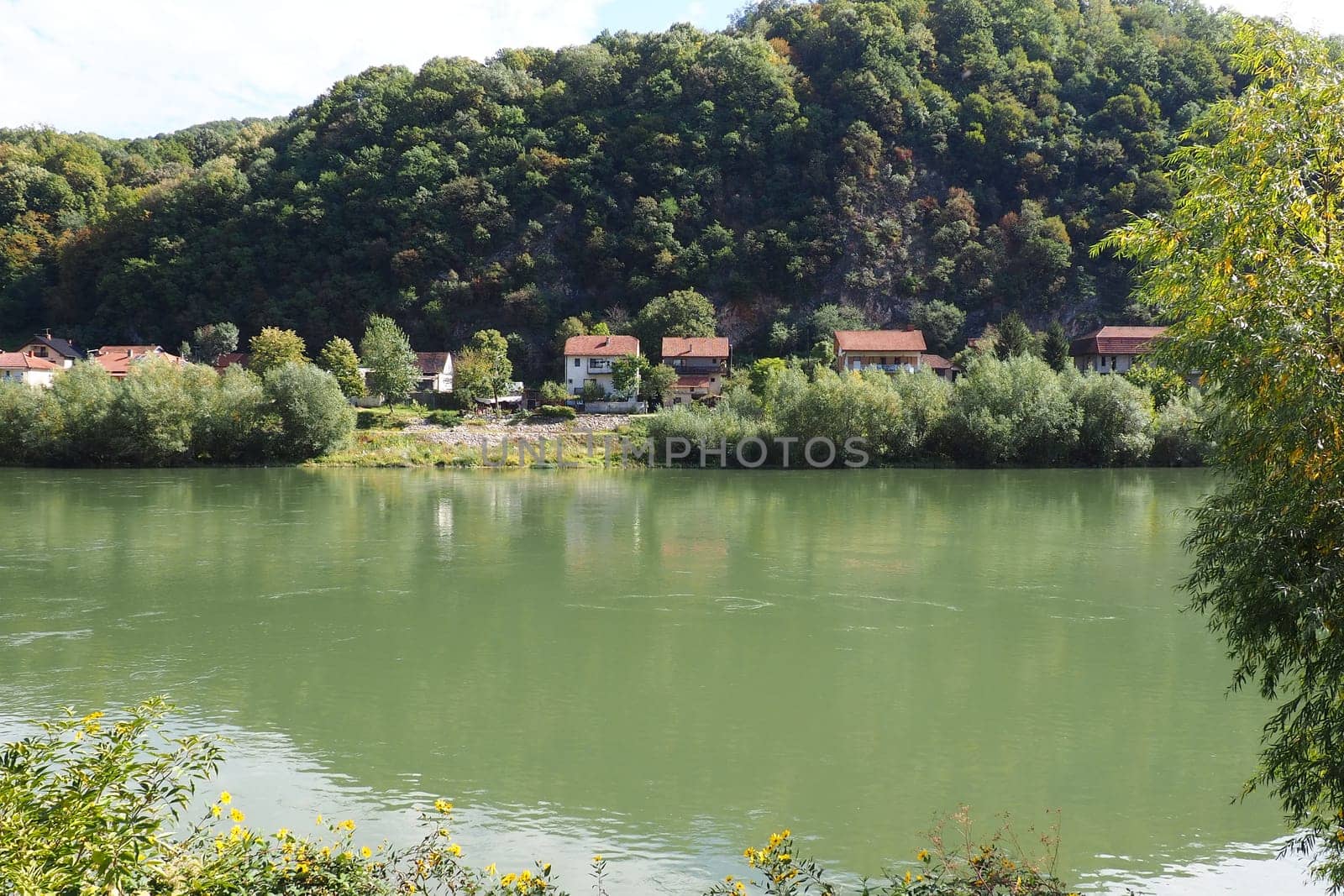 Mali Zvornik, Serbia, September 29, 2022. Drina river near Banja Koviljaca, view of the coast of Serbia from BiH. The flow of water, greenery on the opposite bank of the river. Residential houses