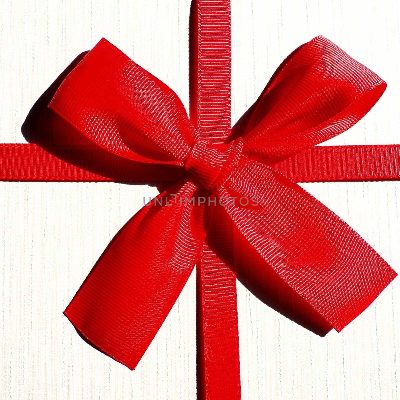 White gift box with red ribbon bow isolated on white background.