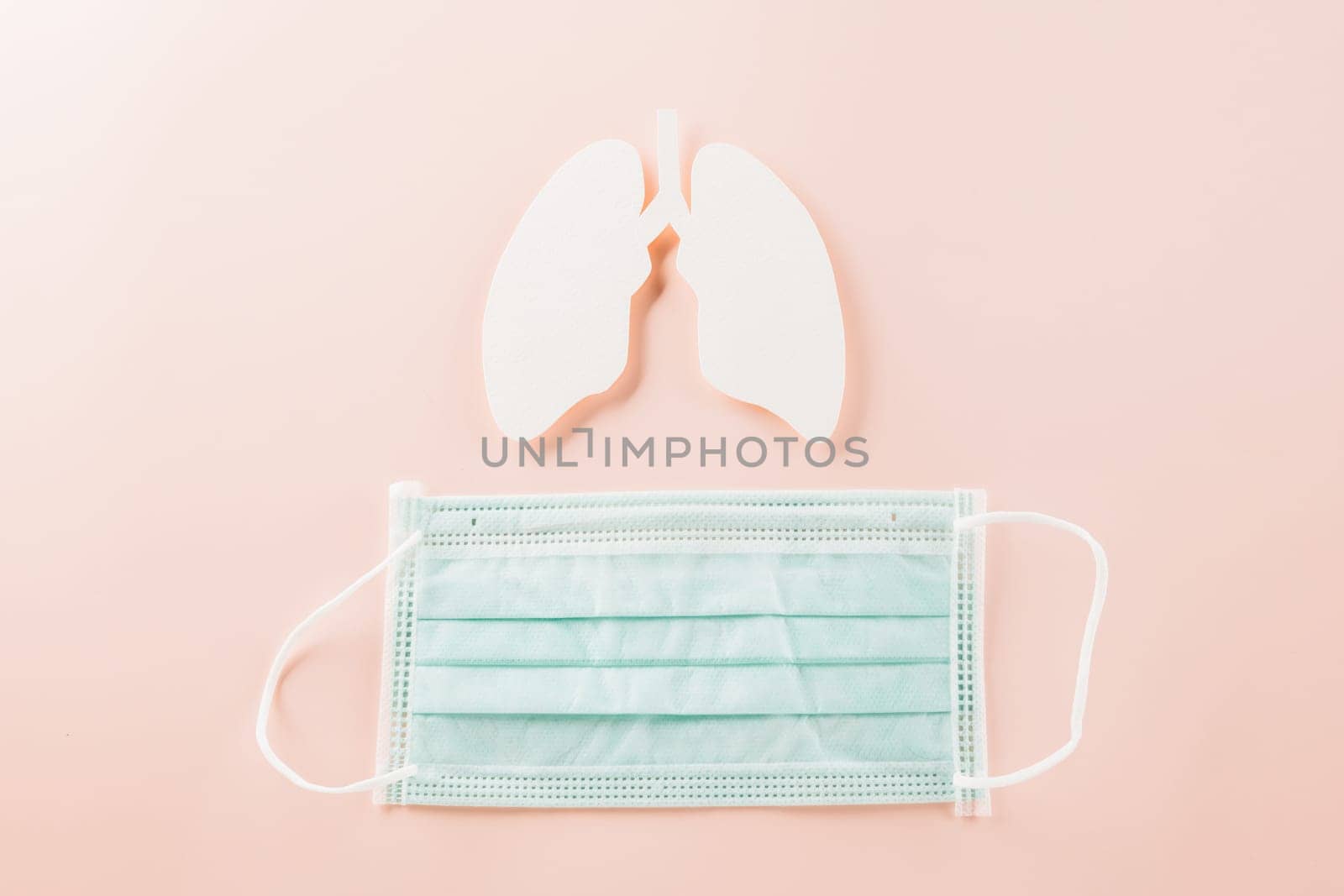 World Tuberculosis Day. Overhead lungs paper symbol and facial medical face mask on pink background, lung cancer awareness, copy space concept of world TB day, banner background, pneumonia awareness