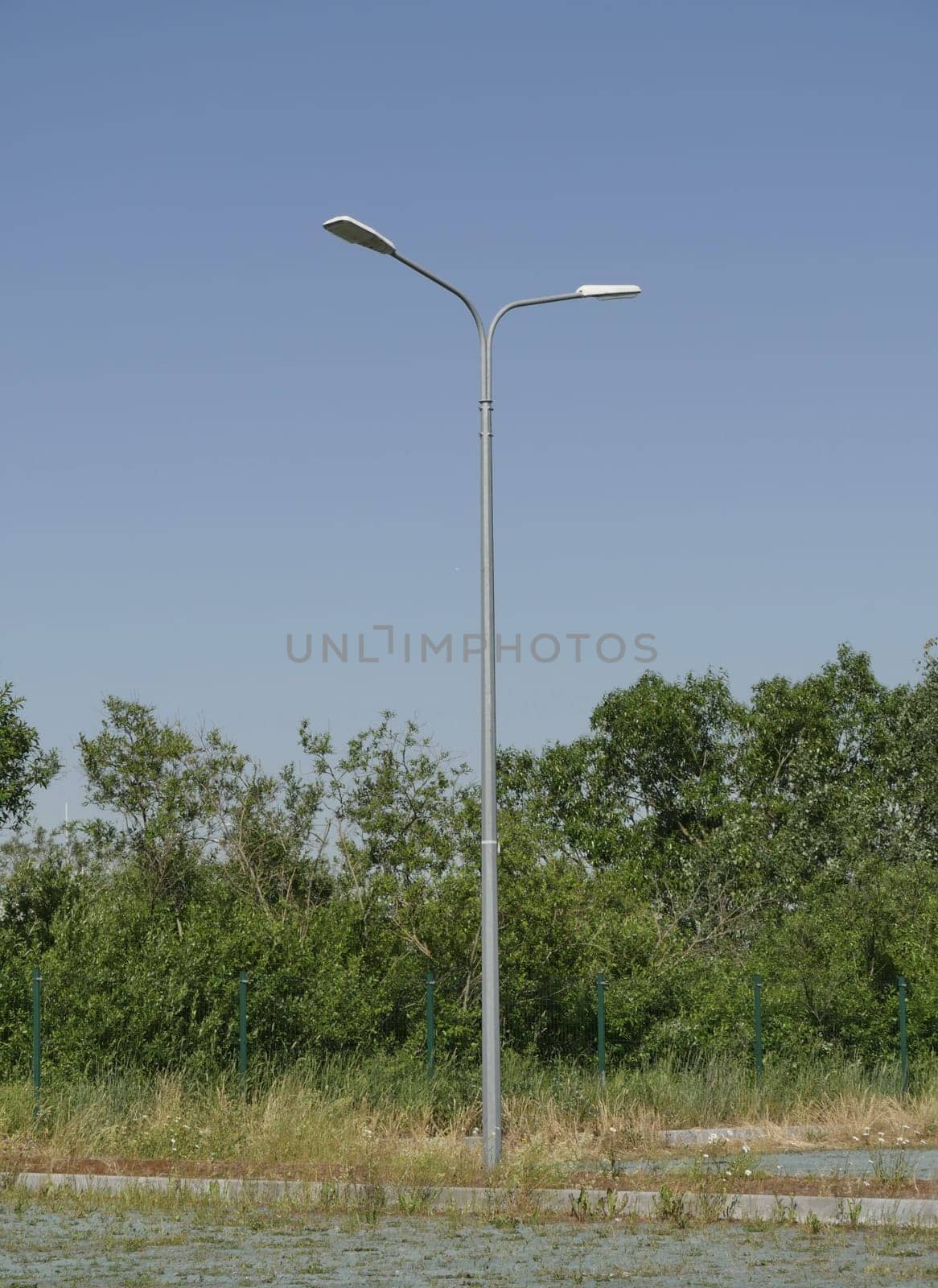 one street pole with two lanterns in nature in the summer day