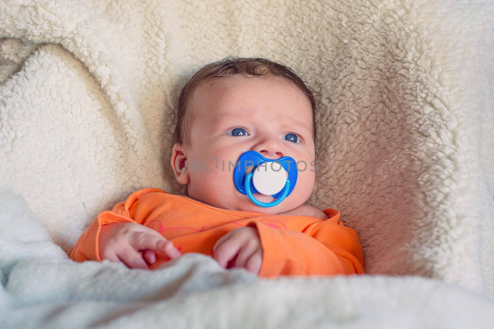 Cute newborn baby boy sucking on a pacifier