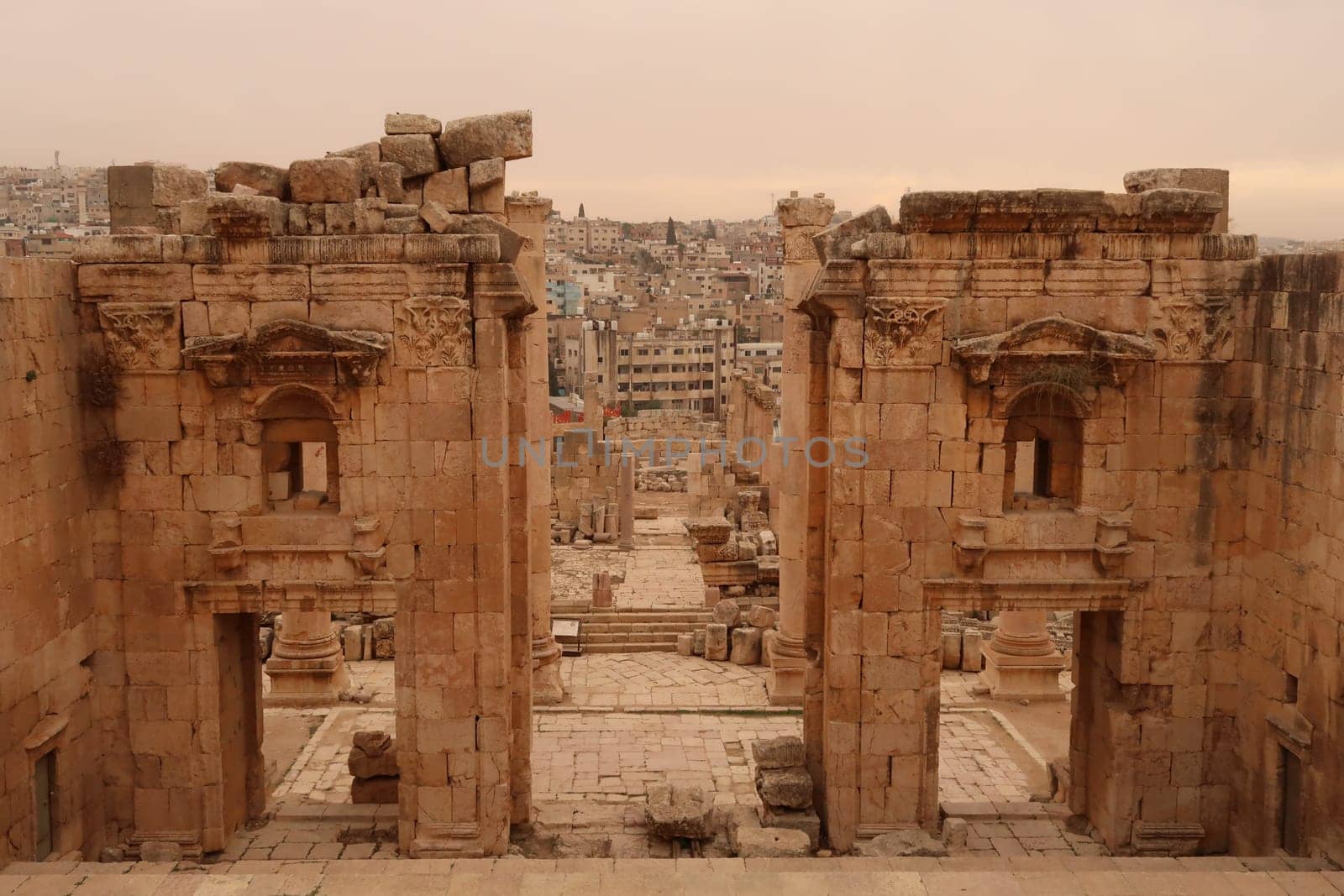 Entrance gate to the Temple of Artemis, Propylaeum of the Sanctuary of Artemis with the modern city of Jerash in the background, Gerasa, Jordan 2021