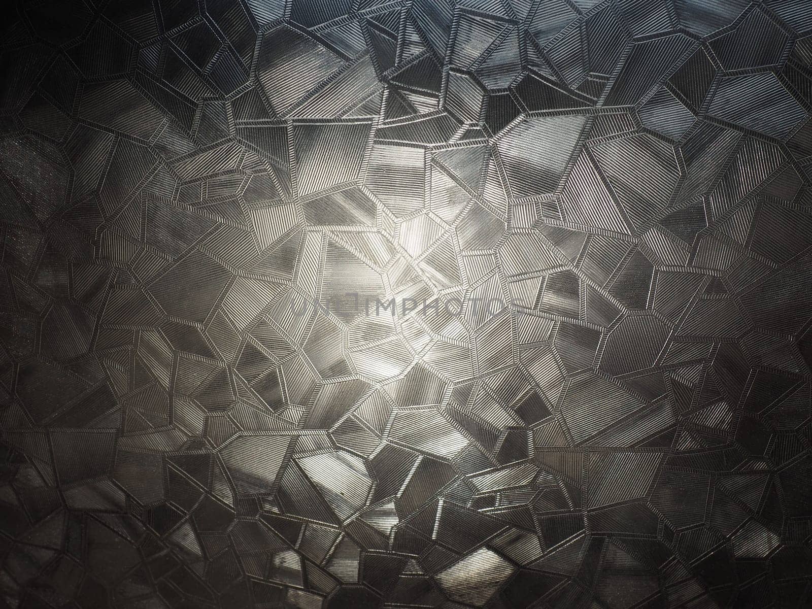 abstract image of corrugated glass on a light and dark background with reflections of light.