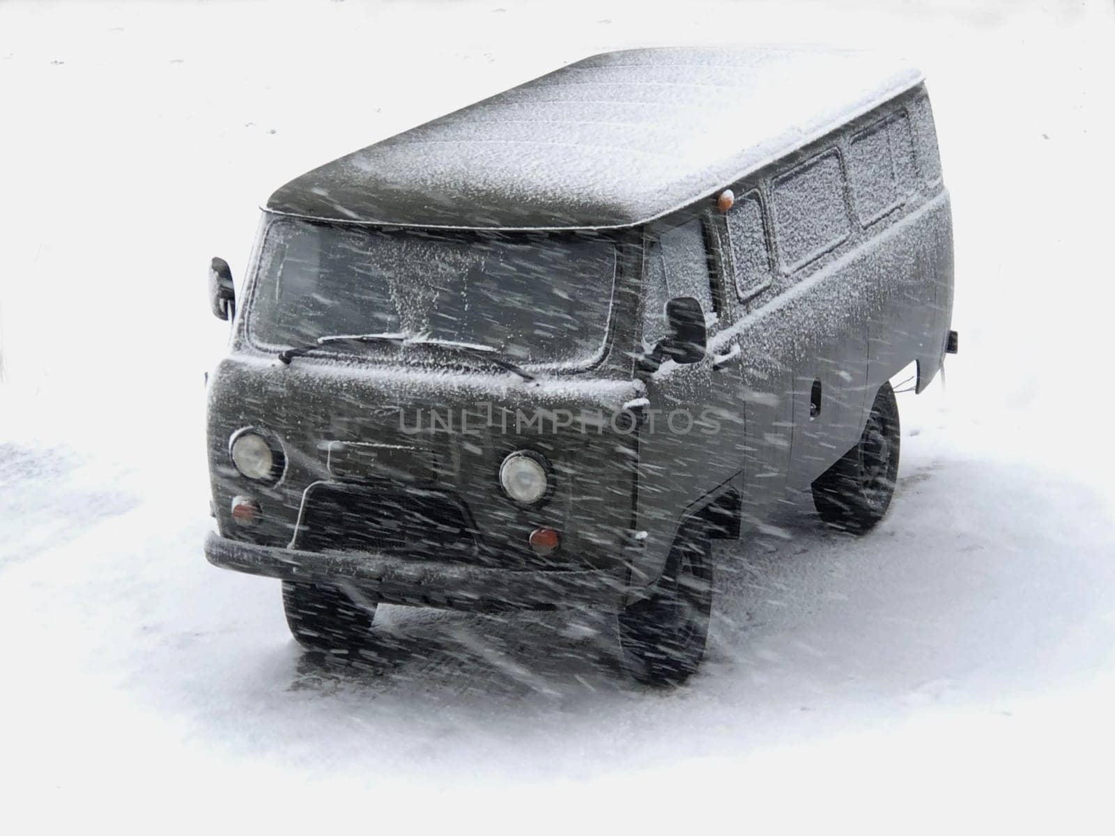 green military SUV in the snow in a blizzard