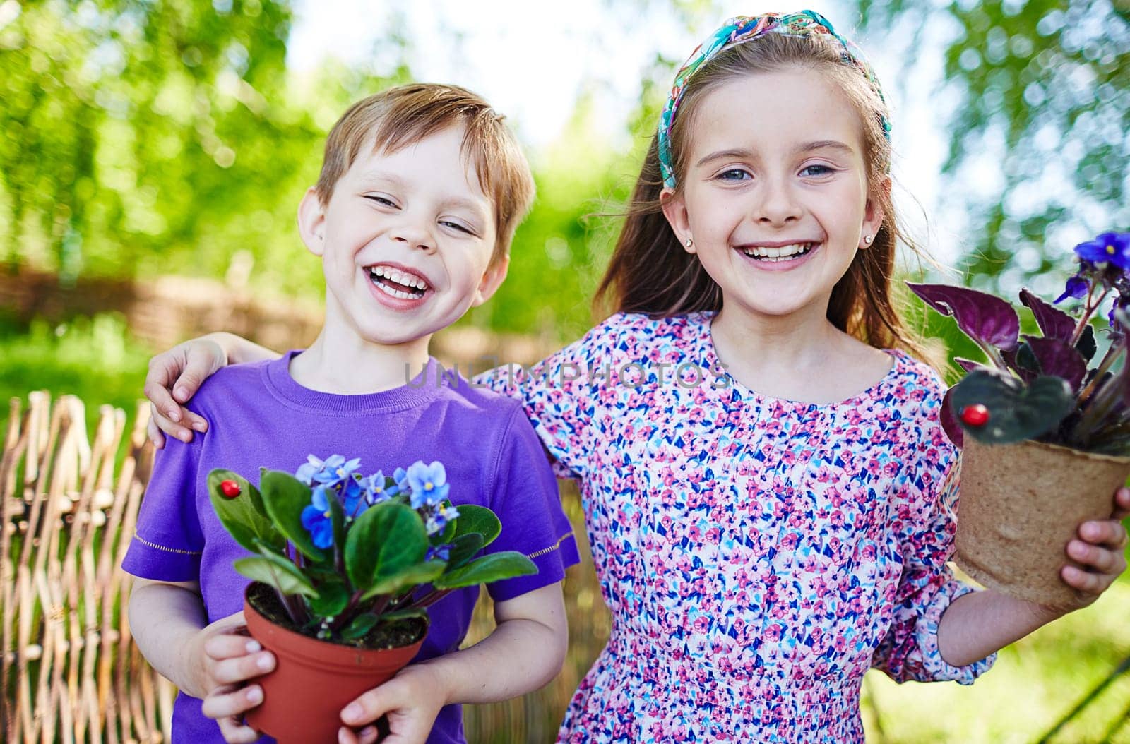 Joyful kids with garden violets looking at camera